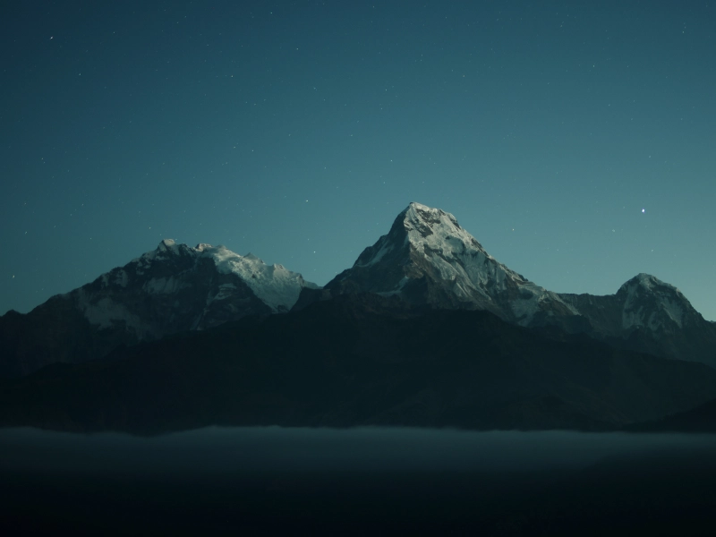 Eine dunkle Bergkette, hinter der das letzte Licht des Abends verschwindet